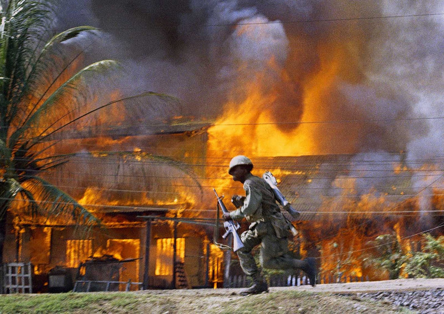 June 1968, Saigon: A U.S. trooper sprints past a burning building, a stark image of the urban warfare that gripped the city. June 1968, Saigon: A U.S. trooper sprints past a burning building, a stark image of the urban warfare that gripped the city.