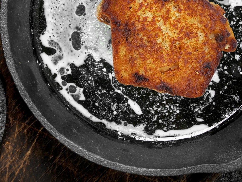 A muffin is frying in a butter filled cast iron pan