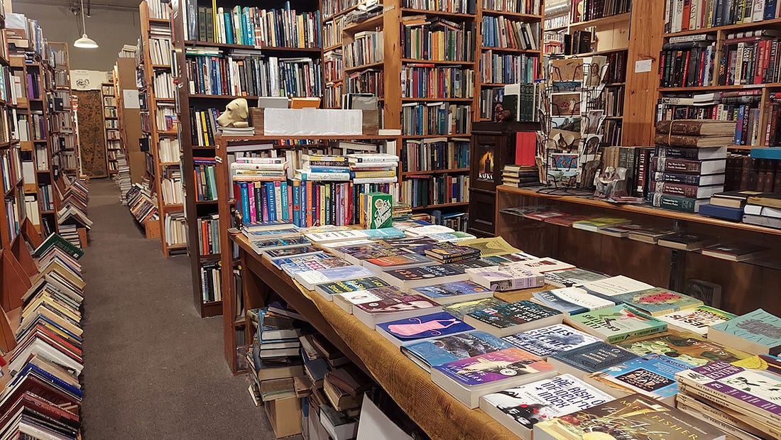 A photograph of a used bookstore with hundreds of books on shelves and tables