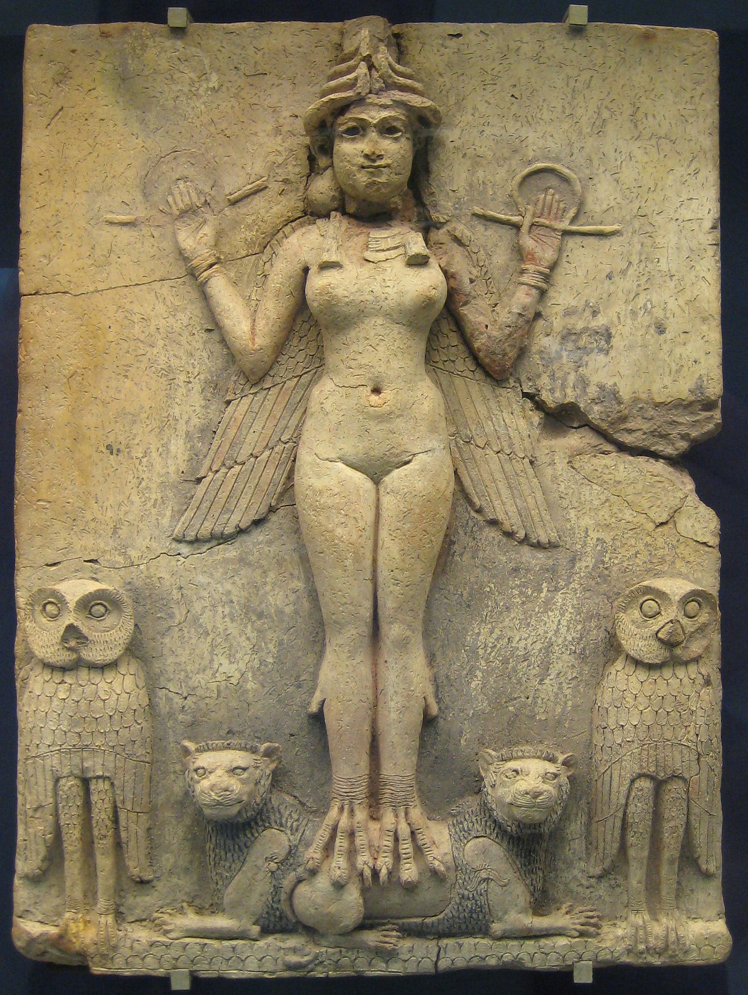 A clay relief of a naked winged goddess with bird's talons for feet, standing on two lions between two owls and holding a rod and ring in each raised hand. A clay relief of a naked winged goddess with bird's talons for feet, standing on two lions between two owls and holding a rod and ring in each raised hand.