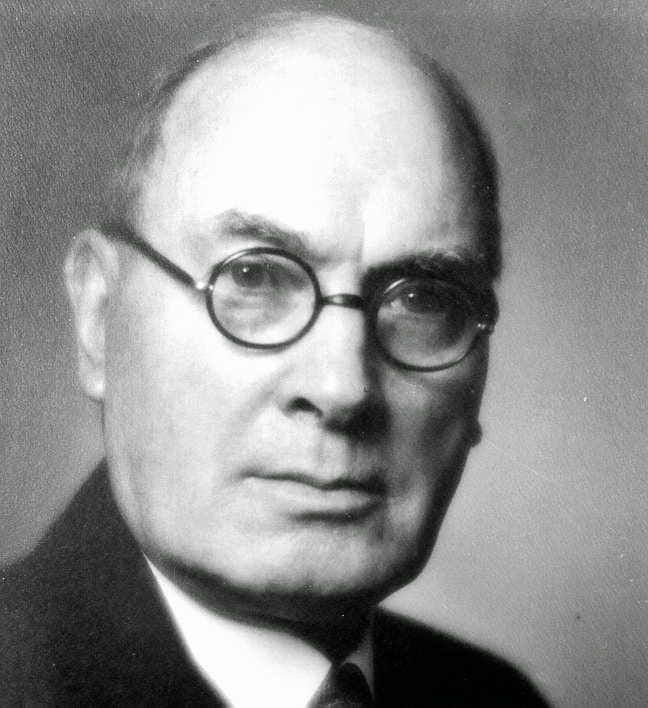 A person wearing glasses and a suit

Description automatically generated