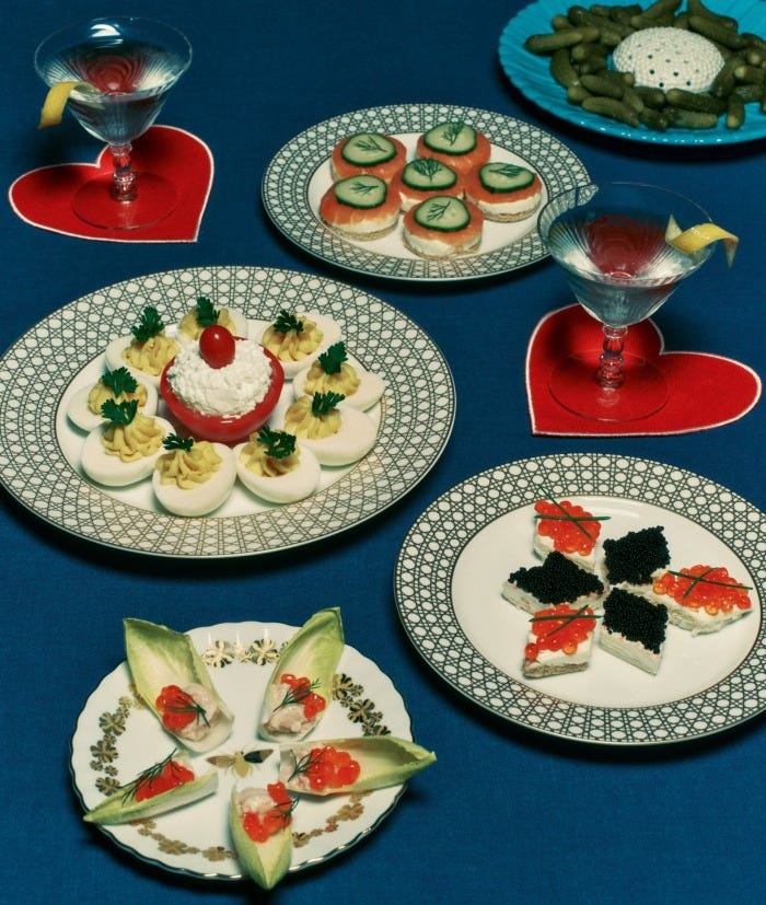 Salmon and cucumber canapés, caviar canapés, endive and salmon canapés, devilled eggs, plate of pickles and Martinis with a twist. Dior Maison porcelain Gold-Tone Cannage Montaigne plates, from £150, and Gold-Tone Bal des Abeilles side plate, £110