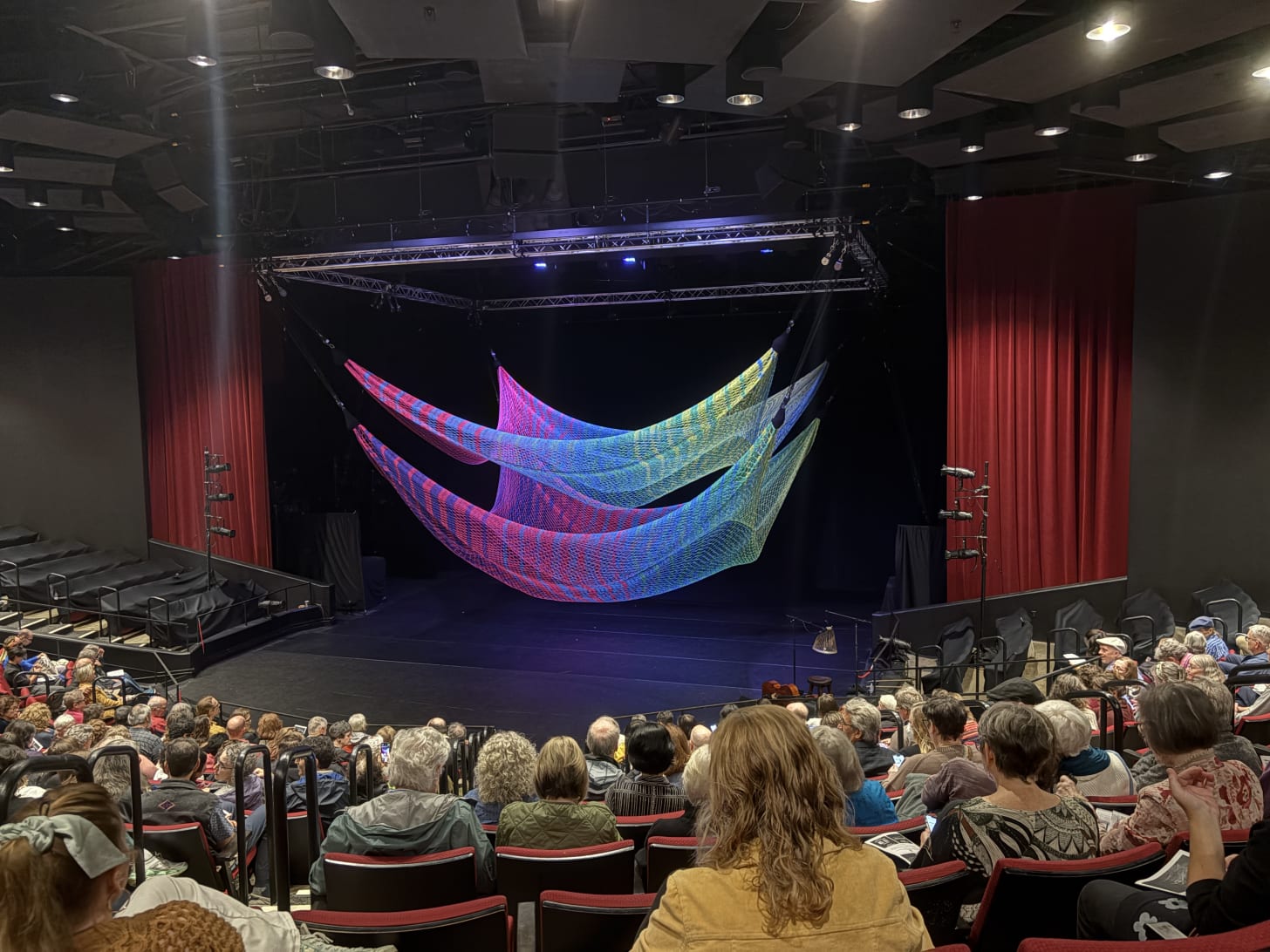 giant nets hanging over a stage in an auditorium with a full crowd watching.