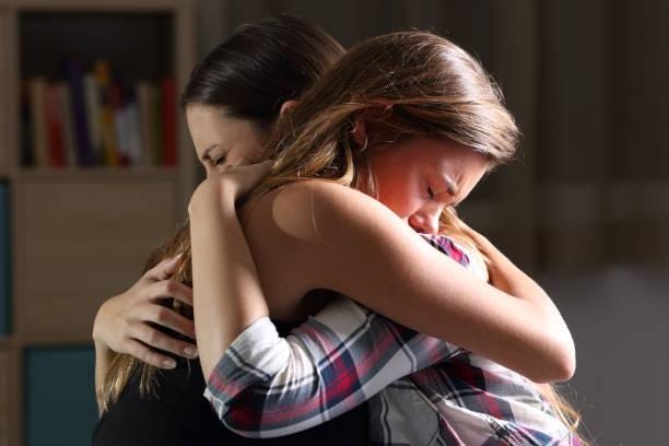 Two sad teens embracing at bedroom Side view of two sad good friends embracing in a bedroom in a house interior with a dark light in the background crying hug stock pictures, royalty-free photos & images