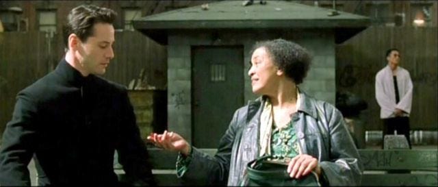 The Oracle offers Neo a piece of candy in The Matrix Reloaded. She already knows the choice he's going to make, but that's not the point of illusions of personal agency, now is it? The Oracle offers Neo a piece of candy in The Matrix Reloaded. She already knows the choice he's going to make, but that's not the point of illusions of personal agency, now is it?
