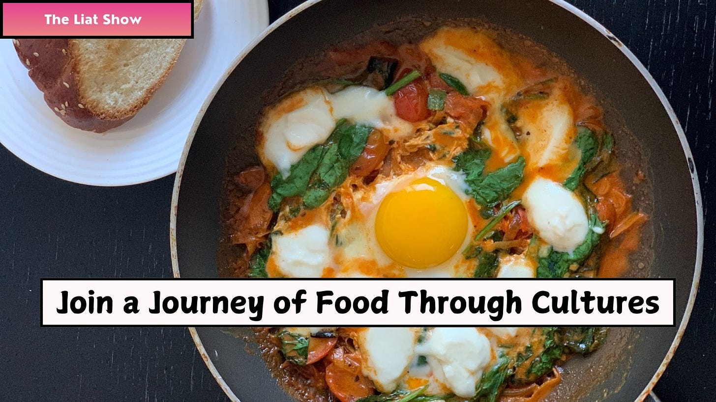 A pan of rich, red shakshuka, cooked and photographed by Liat Portal for Foodie Disorder, featuring a perfectly cooked sunny-side-up egg in the center, surrounded by a deep, slow-simmered tomato sauce with wilted spinach and melted cheese. A white plate with a thick slice of golden-brown challah bread sits beside the pan. Captured as part of The Liat Show, this dish highlights the comforting flavors and cultural heritage of homemade shakshuka.