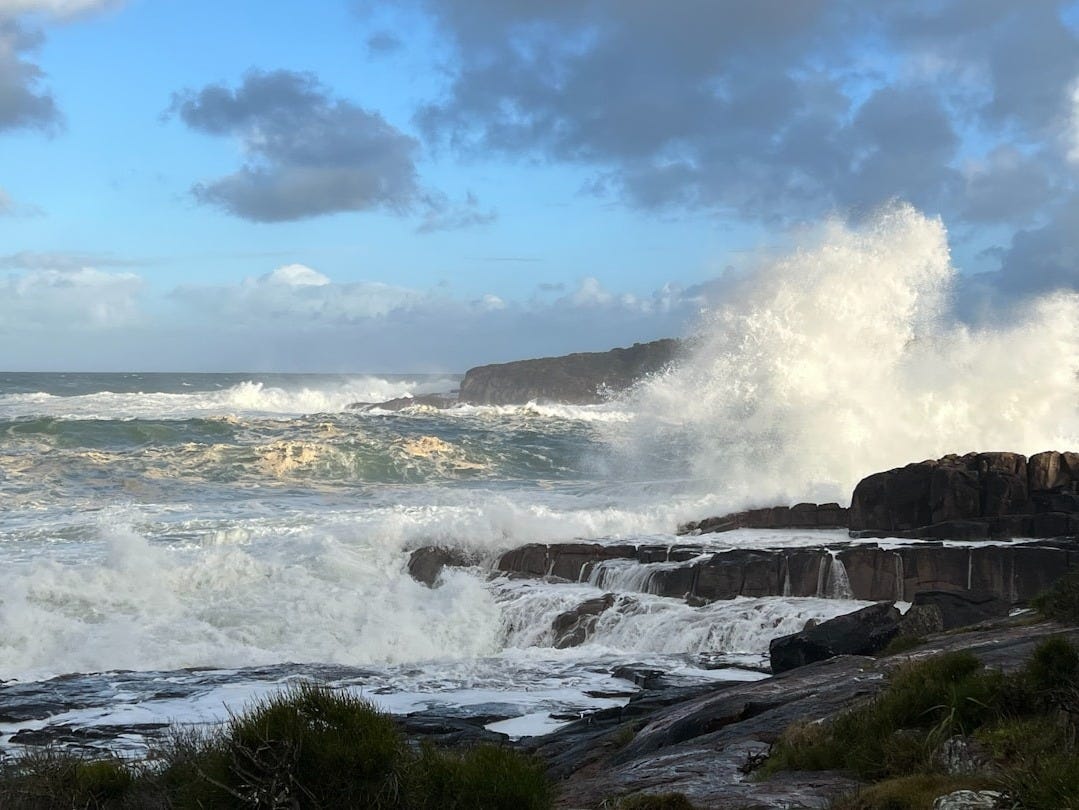 A large wave crashing into a rocky shore