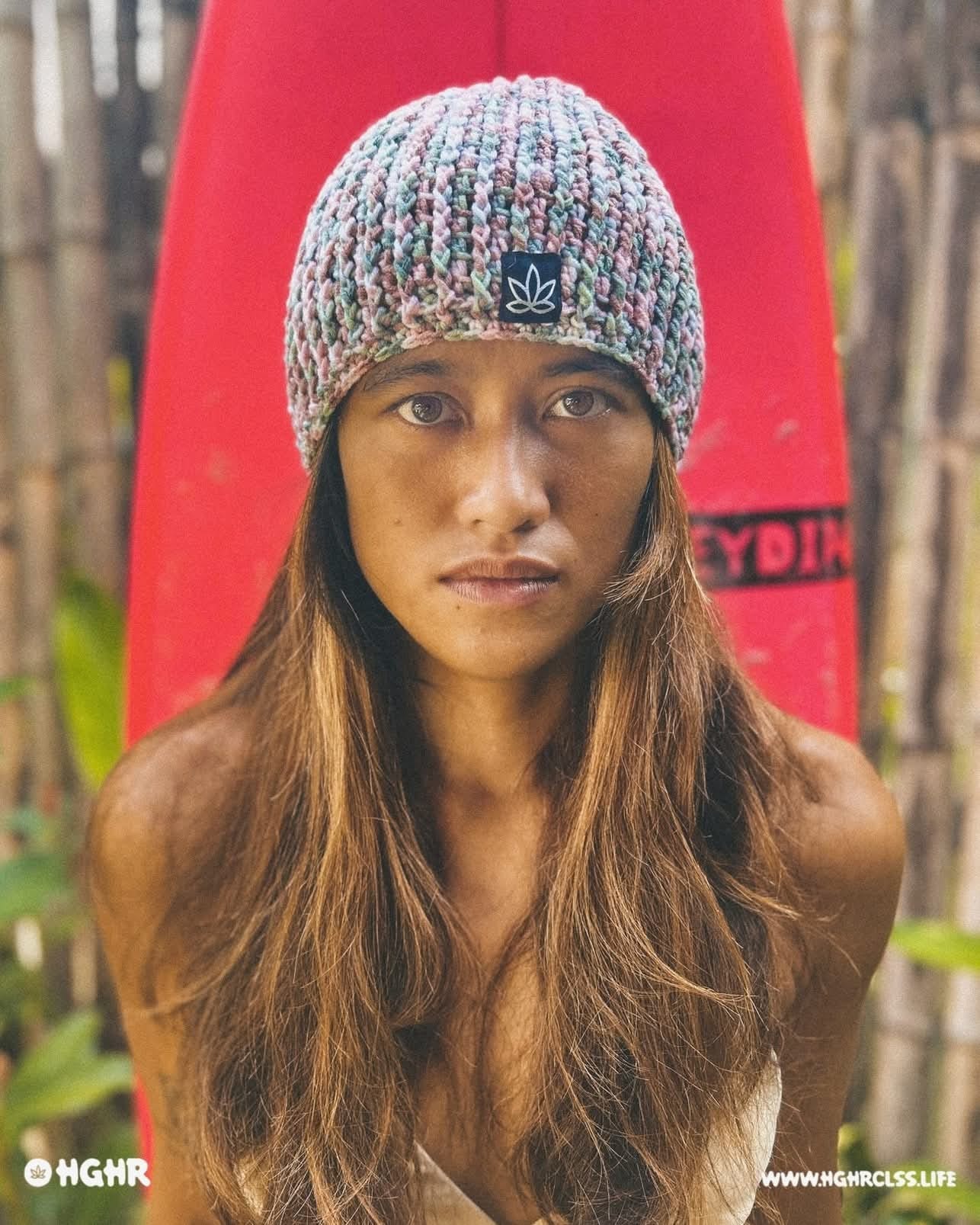 Author, surfer, former rugby pro Astrid Sadaya in a multicolor knit beanie by HGHR, standing in front of a red surfboard. Fierce, grounded, and ready to share travel-inspired meals and cooking tips for fueling high-performance living as our first AMP⚡️ Meal Prep guest contributor. 