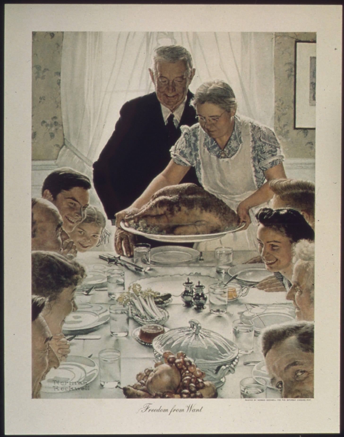 A large family gathered at a table for a holiday meal as the turkey arrives at the table. A large family gathered at a table for a holiday meal as the turkey arrives at the table.
