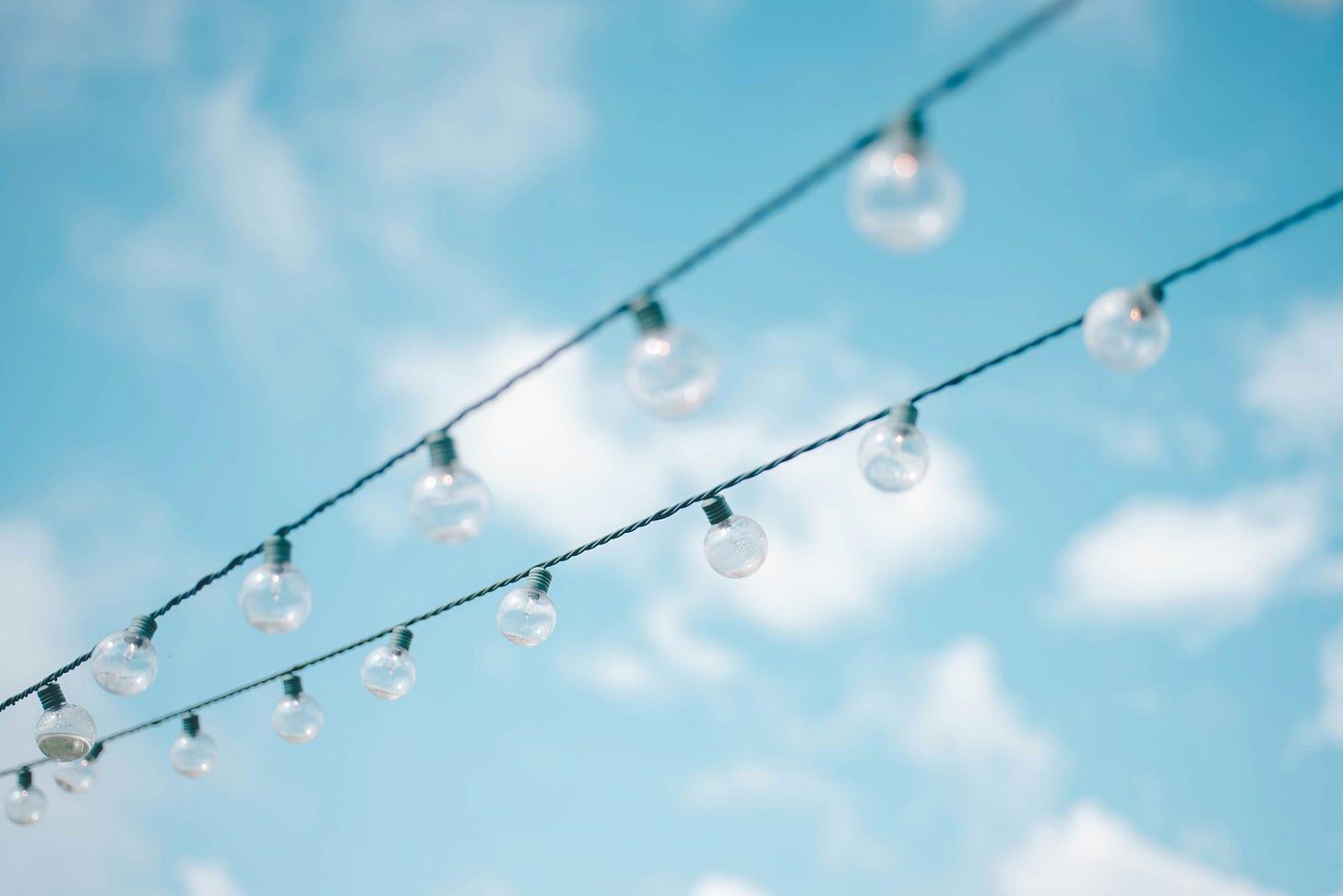 filo elettrico con lampadine su sfondo cielo con nuvole filo elettrico con lampadine su sfondo cielo con nuvole
