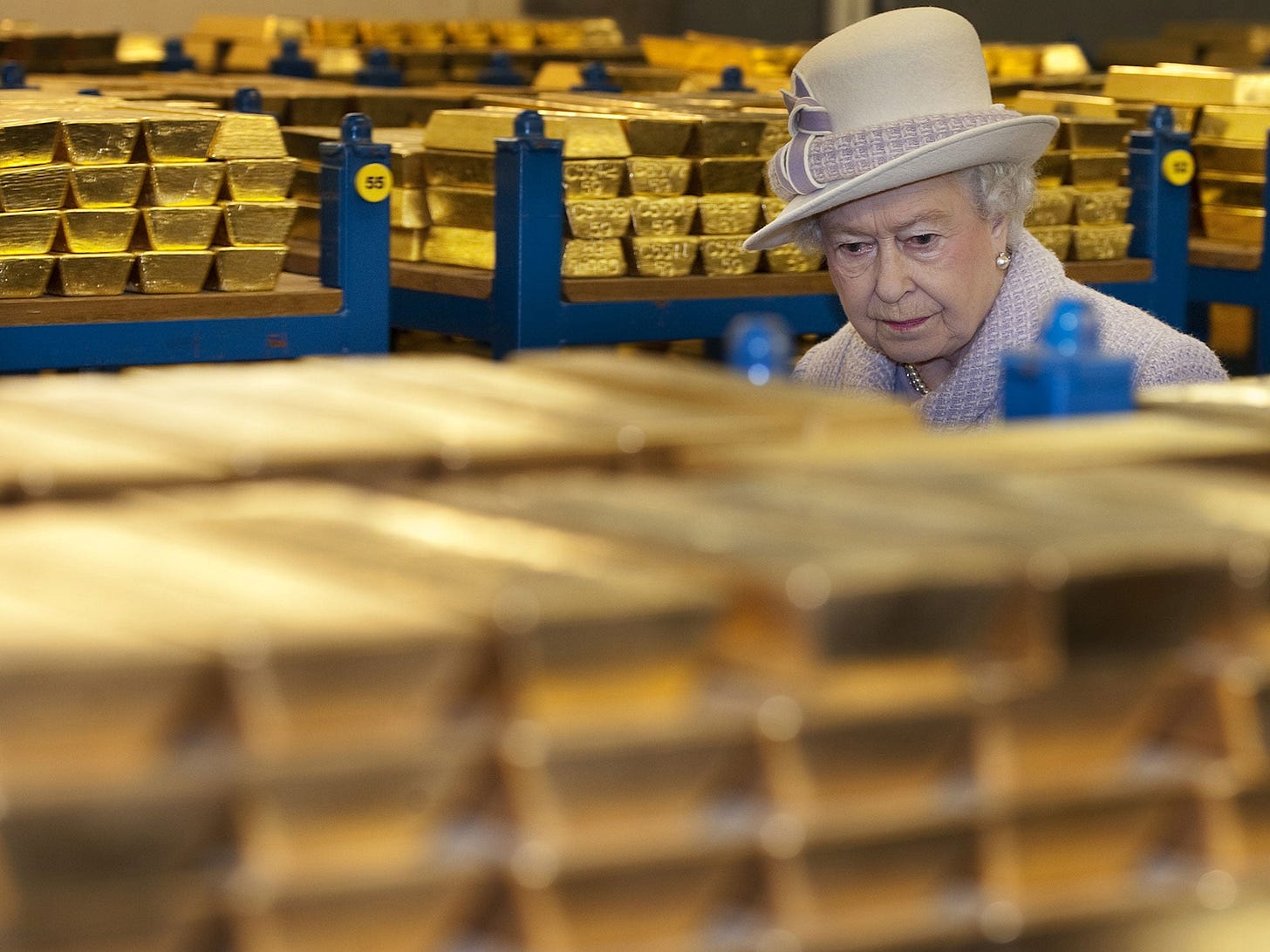 Queen Elizabeth II inspects gold bars stored in a vault, representing physical gold reserves at the Bank of England