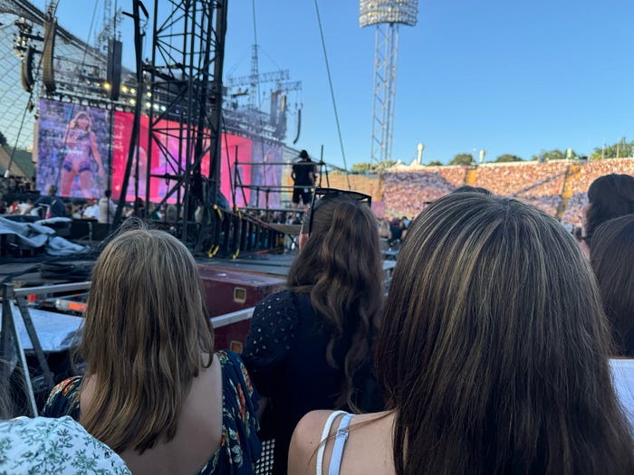 Taylor Swift’s Eras Tour stage in the background, the back of my two daughters’ heads in the foreground. Taylor Swift’s Eras Tour stage in the background, the back of my two daughters’ heads in the foreground.