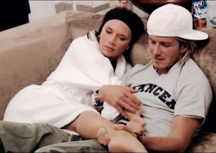 This may contain: a man and woman are sitting on a couch with their arms wrapped around each other