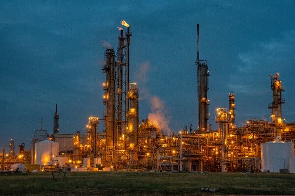 A lit up industrial plant. There are two flames at the top of towers in the middle. A lit up industrial plant. There are two flames at the top of towers in the middle.