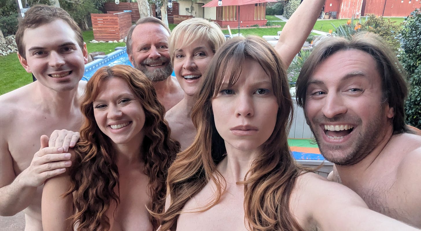Six cast members pose closely together for a selfie outdoors by a backyard pool, smiling and reacting playfully to the camera. From left: Troy Peterson, Eloise Gordon, David McClain, Karen Lasater, and Ian Hayes, with a mid-century home and patio visible behind them.
