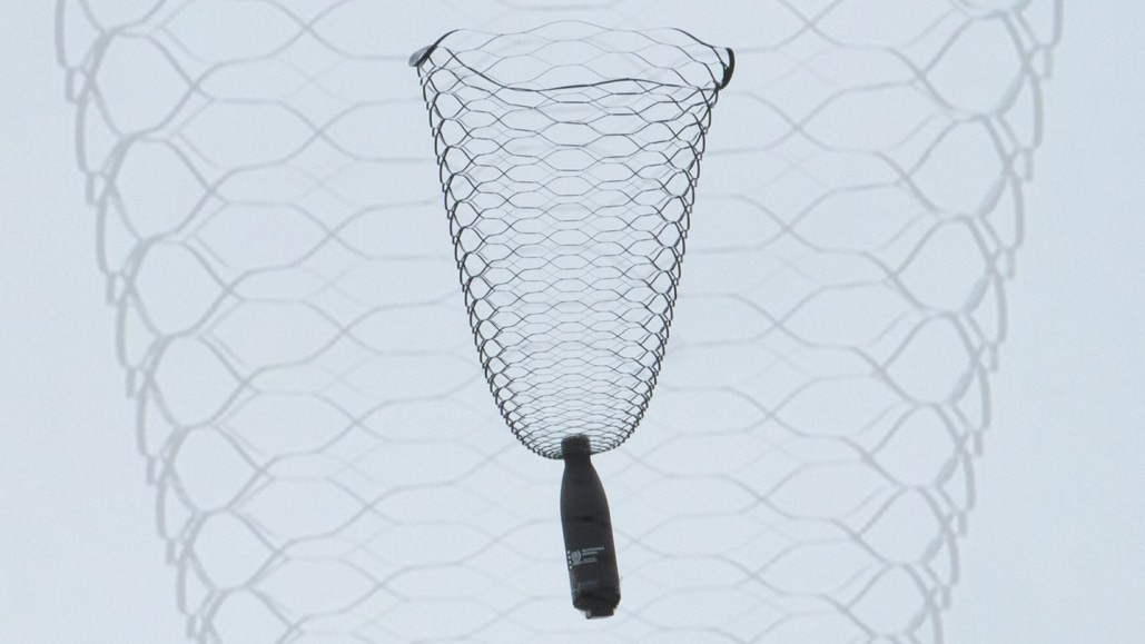 A water bottle dangles from a lacy, vase-shaped parachute.