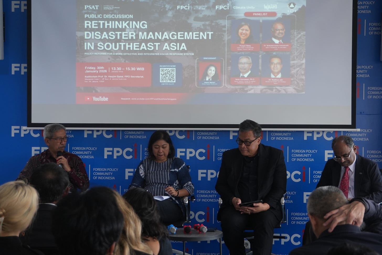 One male moderator, one female panelist, and two male panelists sat in front of a blue backdrop that read "Rethinking Disaster Management in Southeast Asia."