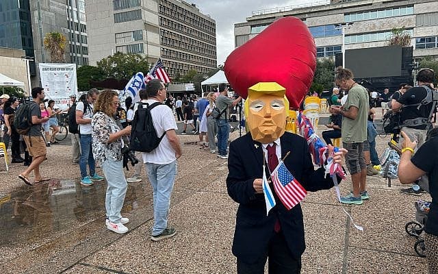 A man wearing a mask of US President Donald Trump celebrates news of a hostage deal in Gaza, Tel Aviv's Hostages Square, October 9, 2025. (Ben Sales/Times of Israel)