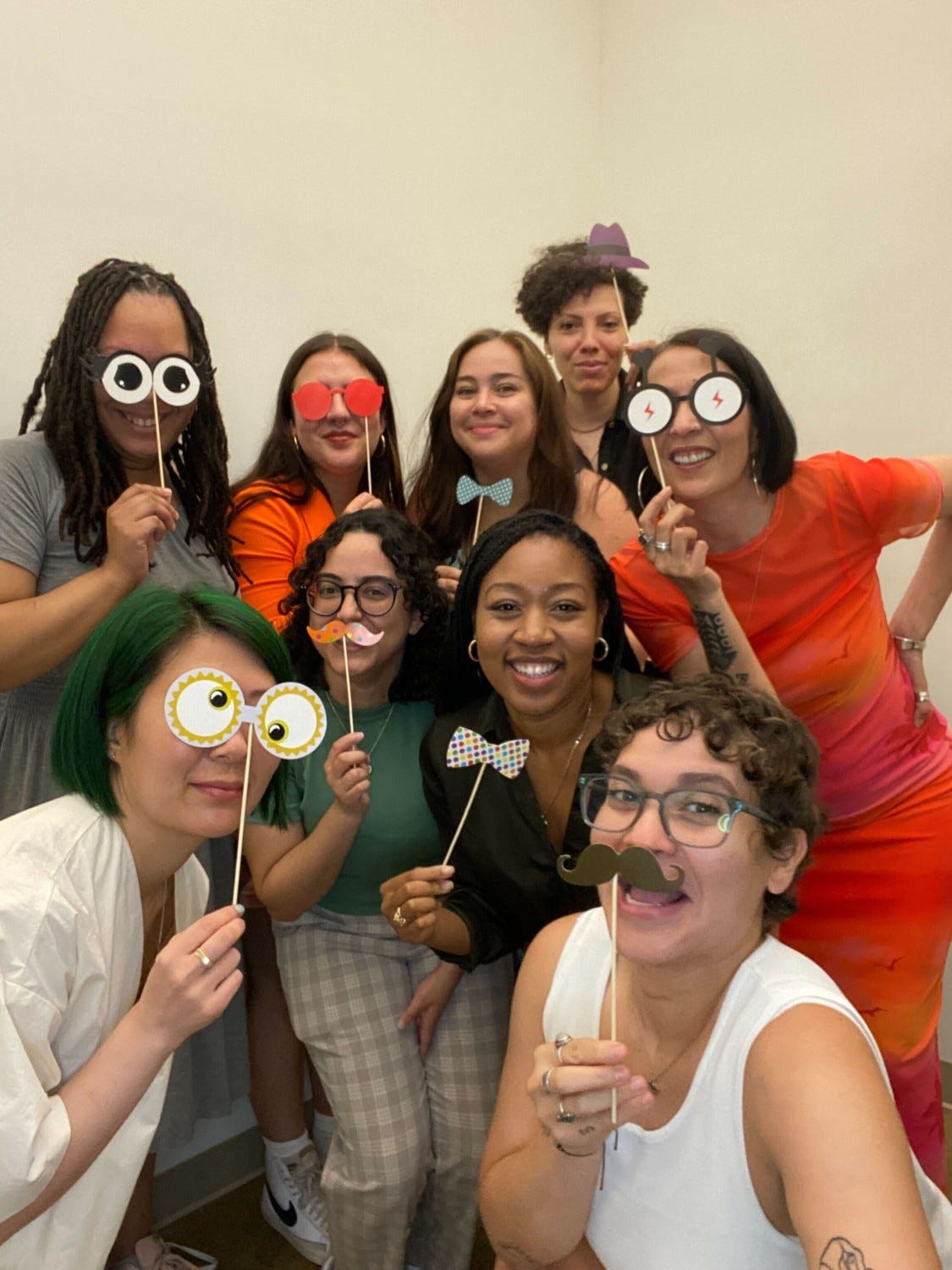 Group shot of Girls Write Now staff and guests with photo booth accessories