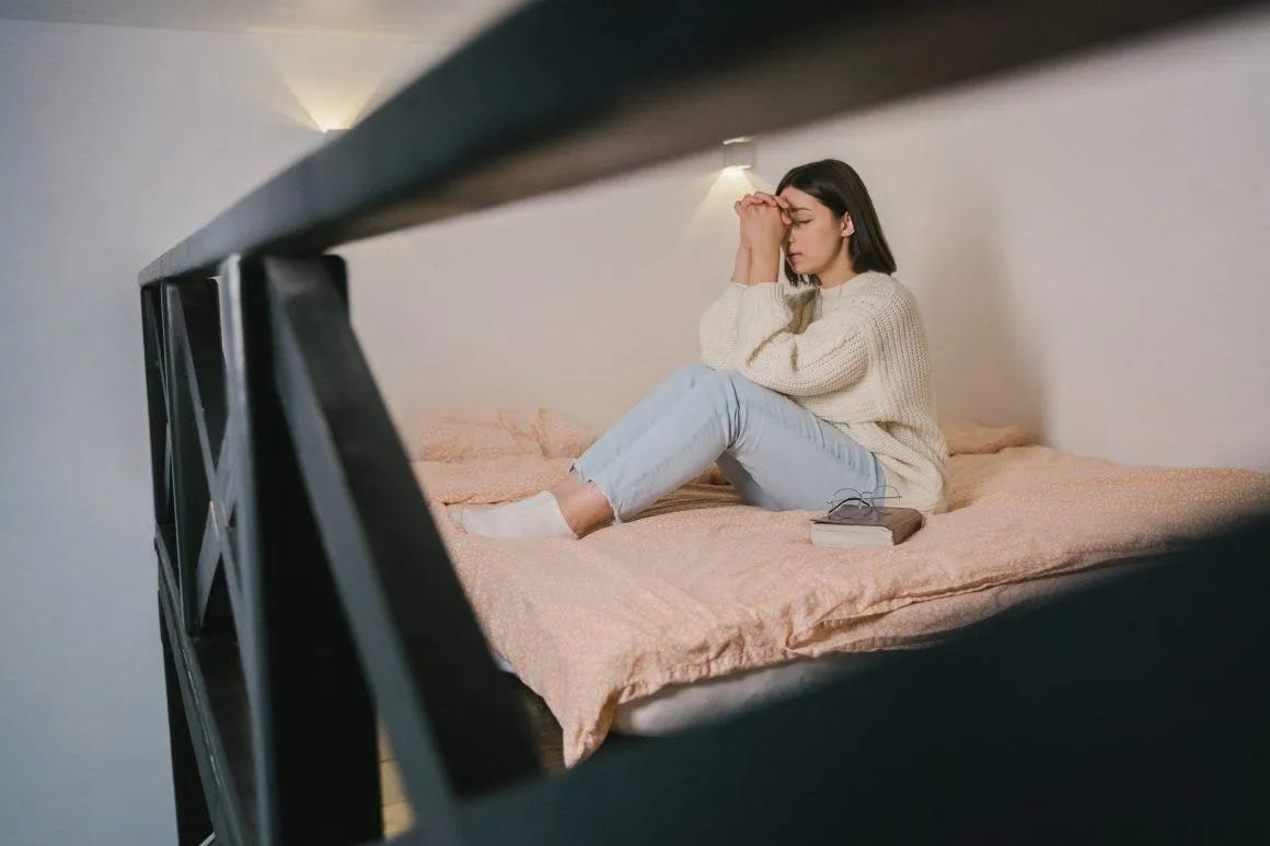 woman in white sweater and blue denim jeans sitting on bed woman in white sweater and blue denim jeans sitting on bed