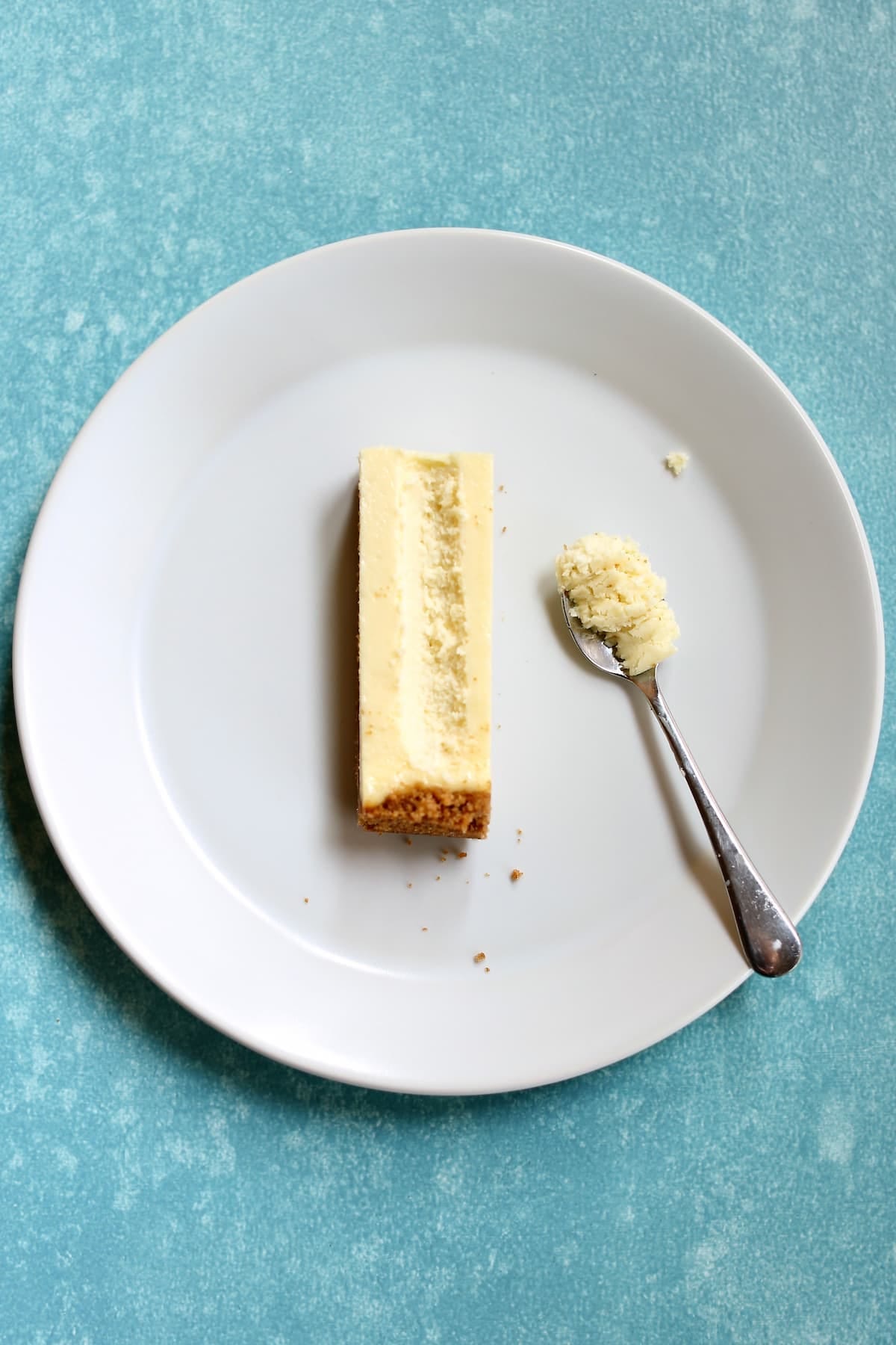 a white plate with a single cheesecake bar on it with the middle scooped out.
