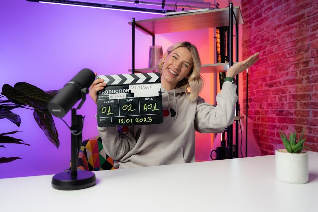 a woman holding a clapper in front of a purple background a woman holding a clapper in front of a purple background