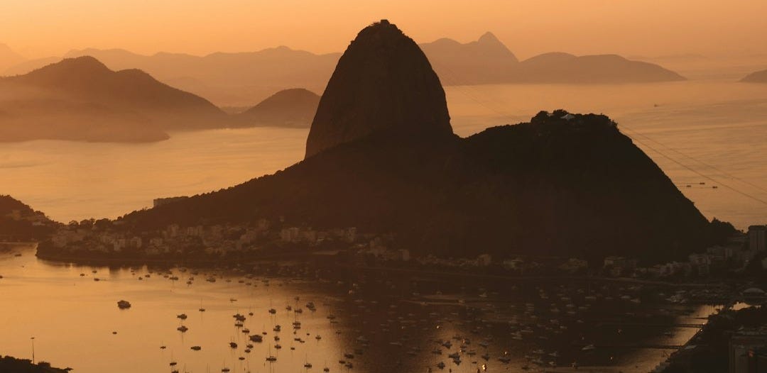silhouette of mountain near body of water during sunset