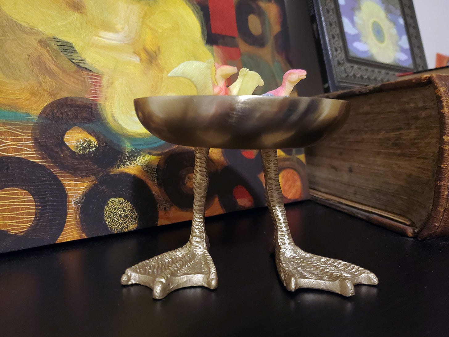 A brass bowl with brass legs and duck feet.