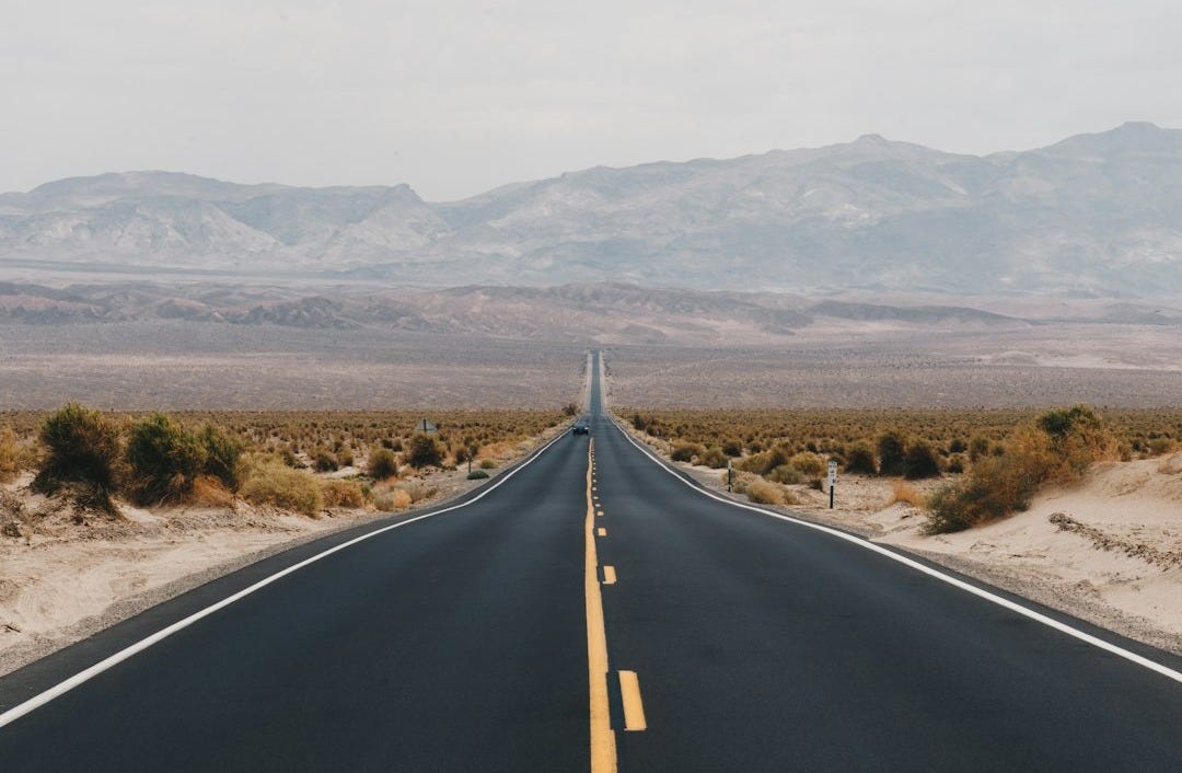 black asphalt road near brown mountains during daytime