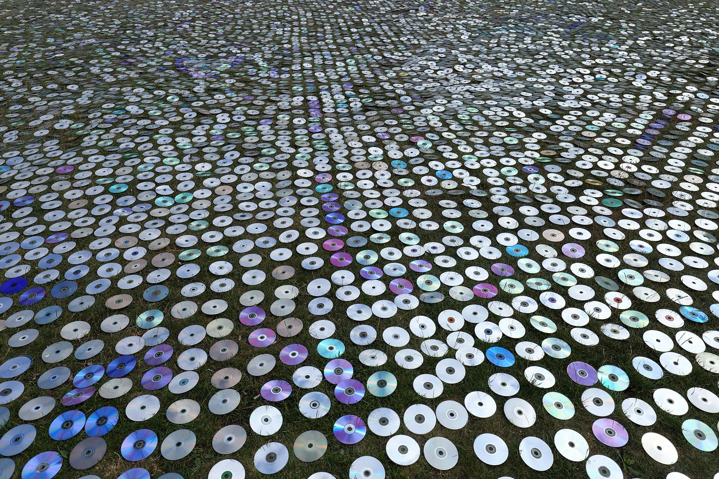 A huge amount of compact disc scattered on a lawn.