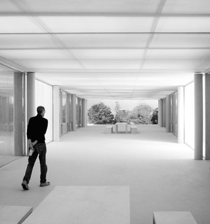 This may contain: a man is standing in an empty room with columns and windows on either side of him