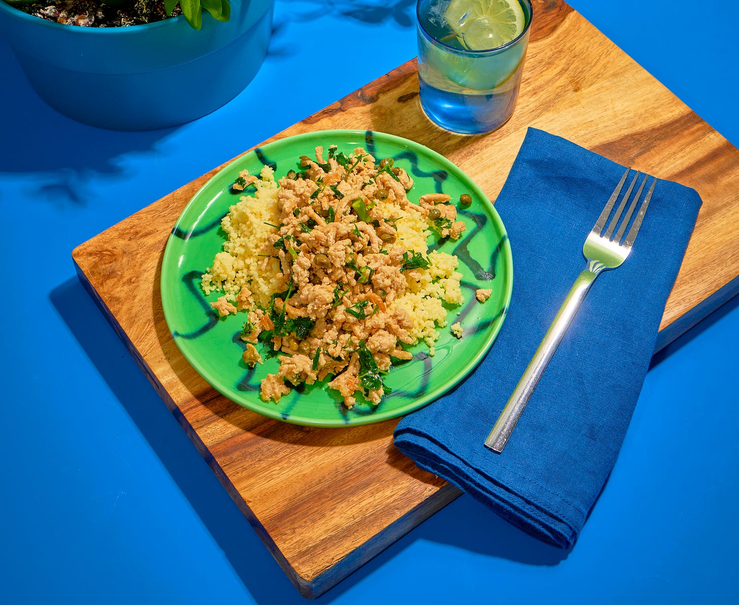 Ground chicken piccata on a green plate on a wooden cutting board, blue background.