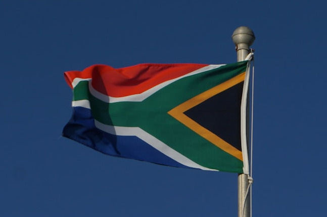 the flag of south africa is flying high in the sky