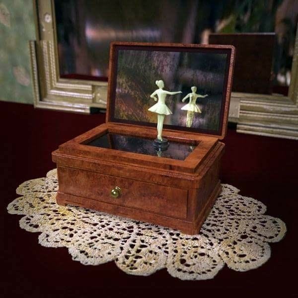 This may contain: a small wooden box with two little figurines in it on a doily This may contain: a small wooden box with two little figurines in it on a doily