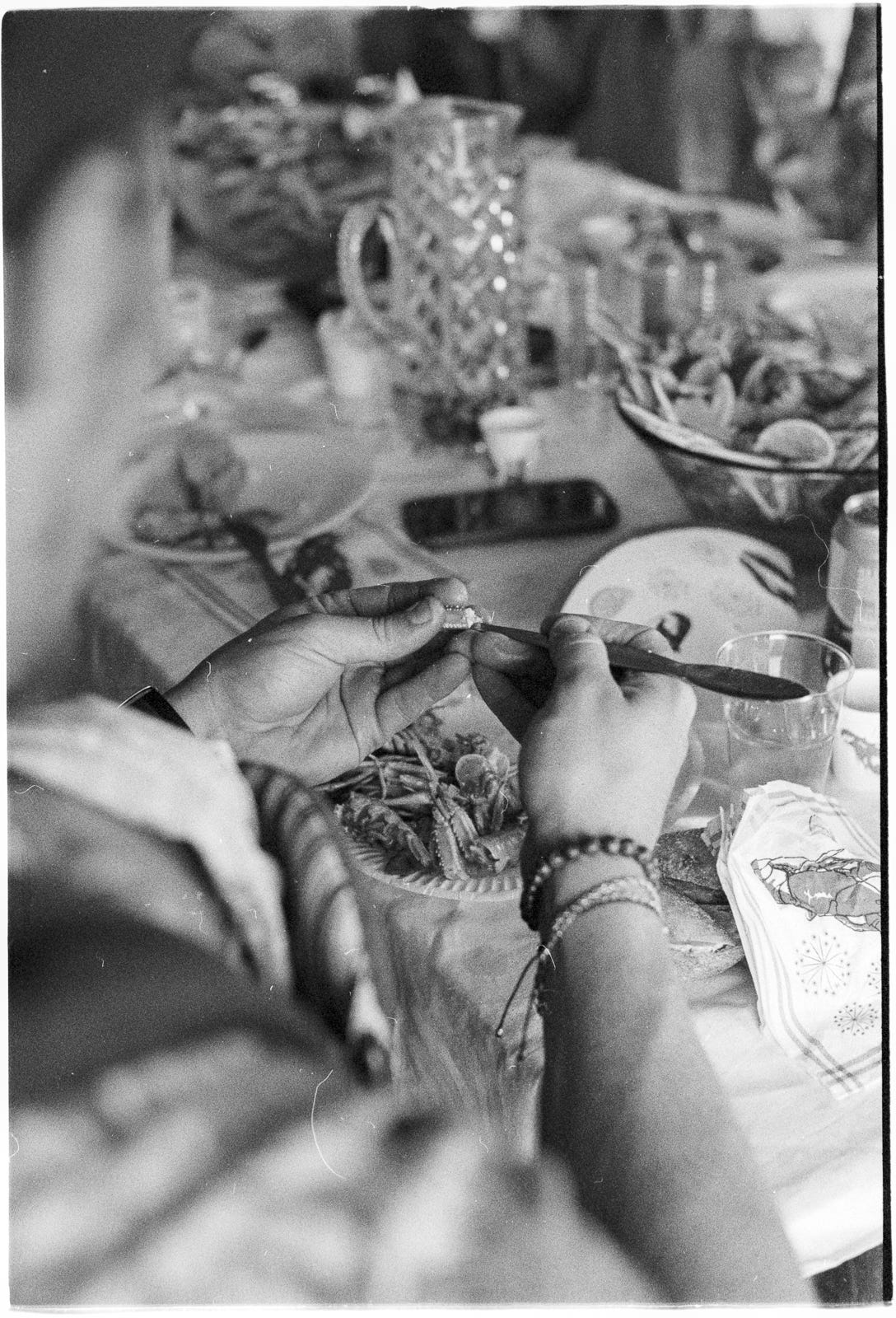 A man eats a crayfish claw with a crayfish-eating implement. In the background is an array of crayfish party accoutrements. A man eats a crayfish claw with a crayfish-eating implement. In the background is an array of crayfish party accoutrements.