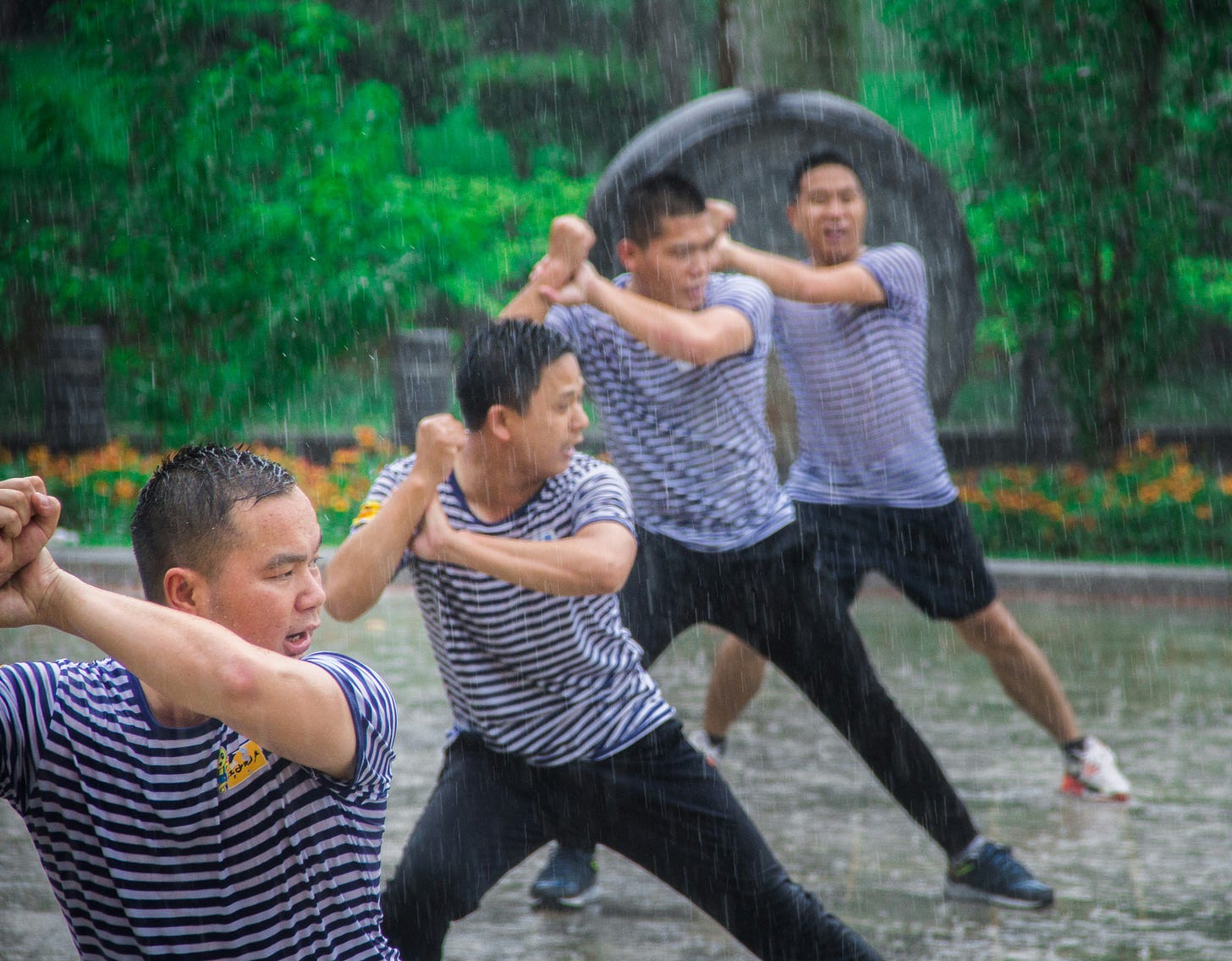 Four men practicing Chinese martial arts in the rain