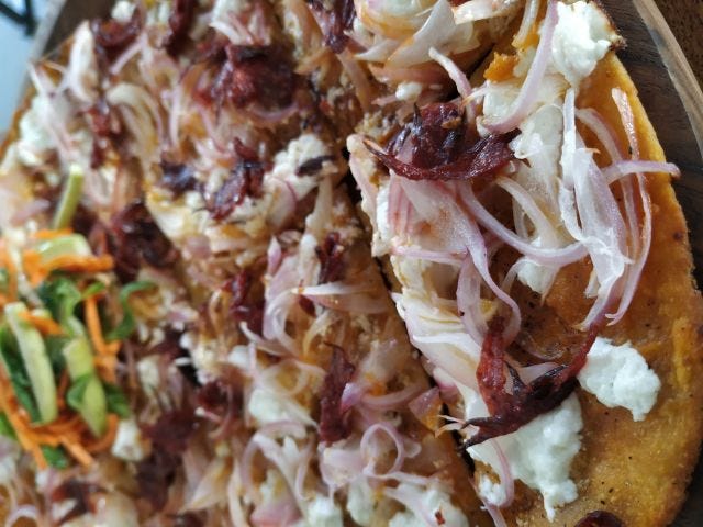 A close up of a pizza with onions, feta cheese and gongura flowers. A close up of a pizza with onions, feta cheese and gongura flowers.