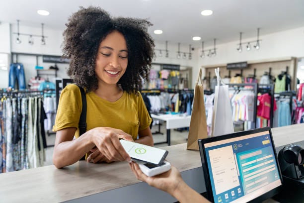 Woman making a mobile payment at a clothing store Happy Latin American woman making a mobile payment at a clothing store - contactless payment concepts checkout register stock pictures, royalty-free photos & images Woman making a mobile payment at a clothing store Happy Latin American woman making a mobile payment at a clothing store - contactless payment concepts checkout register stock pictures, royalty-free photos & images
