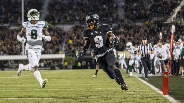 UCF running back Adrian Killins Jr. (9) races into the end zone for a touchdown in front of USF defensive back Devin Studstill (8) during the first half of the "War on I-4" rivalry. (WILLIE J. ALLEN JR. | AP) UCF running back Adrian Killins Jr. (9) races into the end zone for a touchdown in front of USF defensive back Devin Studstill (8) during the first half of the "War on I-4" rivalry. (WILLIE J. ALLEN JR. | AP)