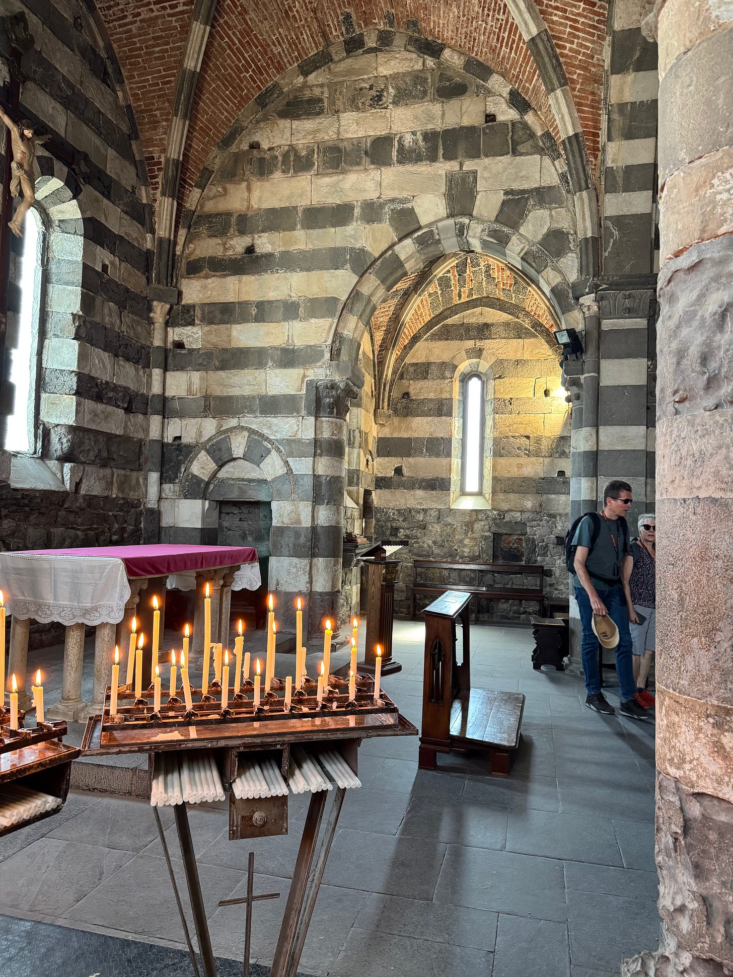 Corner or stone chapel showing vault and simple altar with slender lit candles