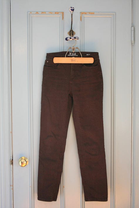 Three pairs of pants pictured; from left to right black jeans, blue jeans, brown pants