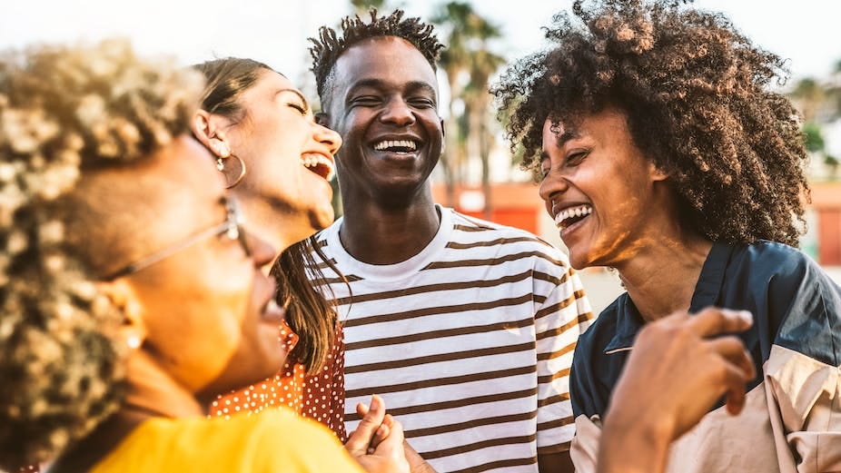 Four young people of university-going age laugh together 
