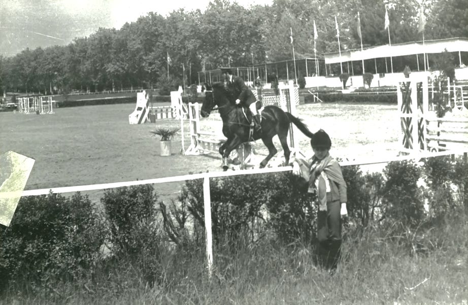 A captivating 1940s scene: a stern Cavalry Officer during a military exercise, contrasted by a curious boy in the foreground seemingly posing for the camera, offering a unique glimpse into the past.