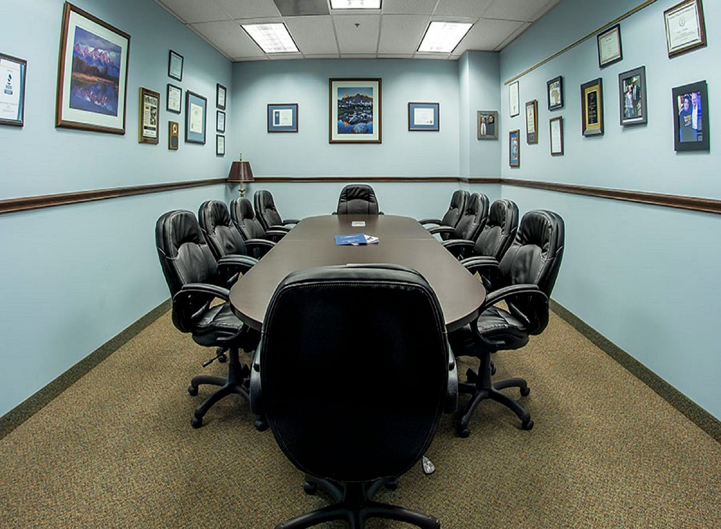 a boardroom with teal walls and lots of photos, with many leather chairs around the table