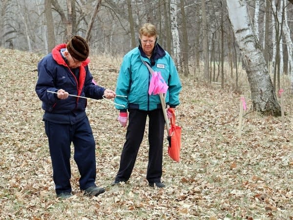 a man and a woman stand in a wooded area