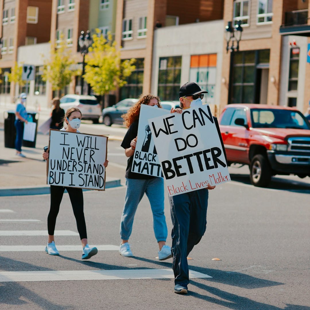 man in black and white long sleeve shirt holding white and black signage man in black and white long sleeve shirt holding white and black signage