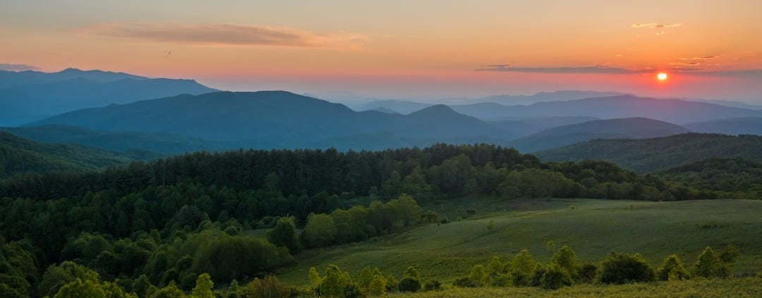 the sun is setting over the mountains in the distance