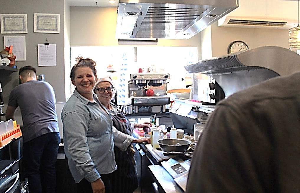 A group of people standing in a kitchen

Description automatically generated