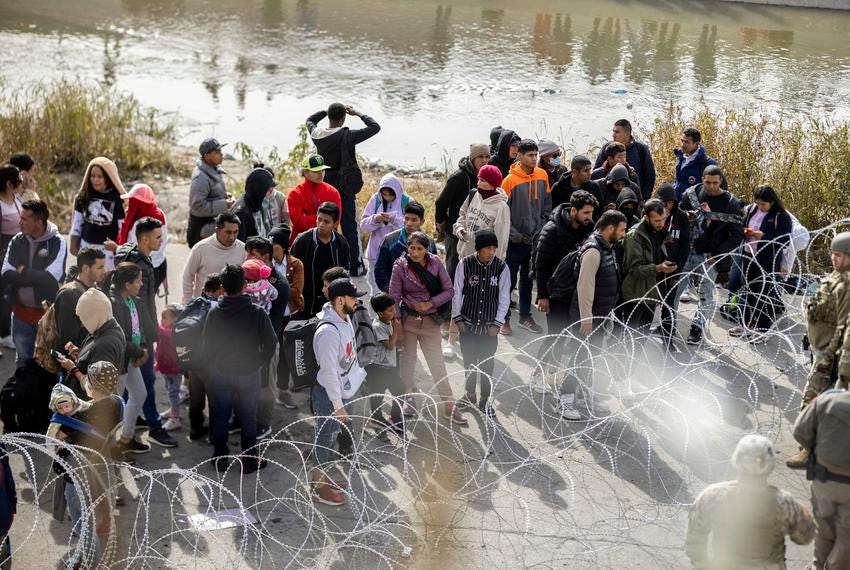 Barbwire separates migrants and the Texas National Guard and Texas DPS officers on the banks of the Rio Grande, on Dec. 20, 2022, in El Paso. Over 400 personnel have been sent to this border sector by Gov. Abbott after El Paso city officials declared a state of emergency.
