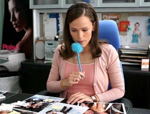 This may contain: a woman sitting at a desk with a lollipop in her hand and pictures on the table